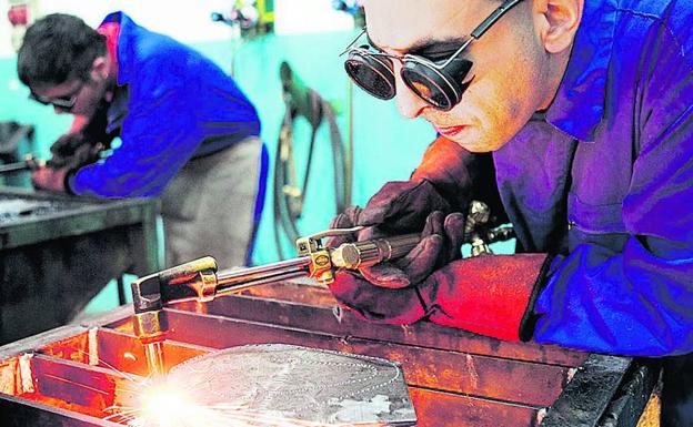 Dos trabajadores realizan labores de soldado en una empresa.
