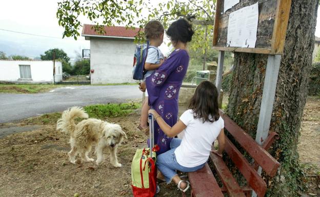 Unos niños esperan la llegada del autobús escolar.