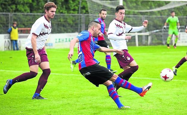 Un jugador del Leioa saca el balón ante dos rivales.