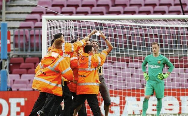 El espontáneo del Camp Nou se hace un selfie mientras es retirado por la seguridad. /EFE