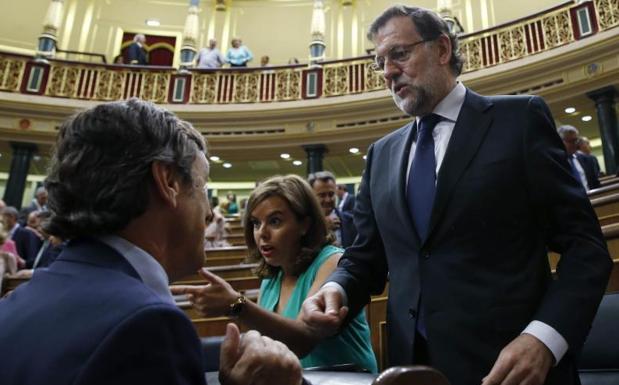 Mariano Rajoy conversa con el portavoz parlamentario del PP, Rafael Hernando, en presencia de la vicepresidenta, Soraya Sáenz de Santamaría./EFE