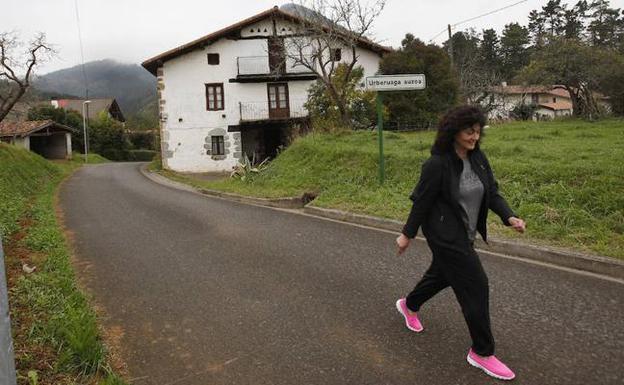 Una vecina transita por el camino del barrio Urberuaga de Forua. / M. S.