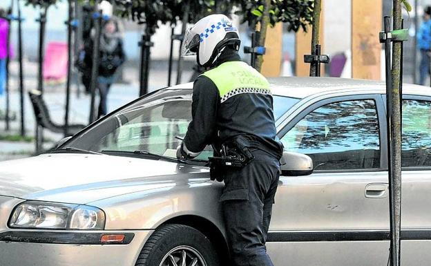 Un agente local multa a un vehículo mal estacionado. /Igor Aizpuru