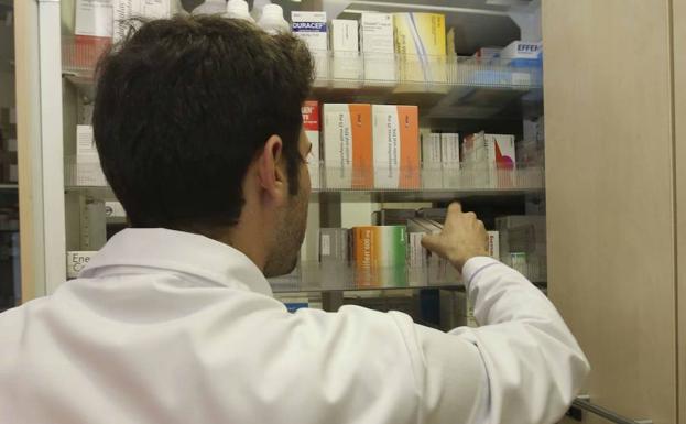Un farmacéutico busca un medicamento en un estante de su botica. /R.C.