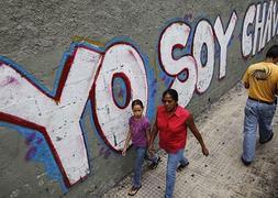 Un grupo de personas camina junto a un letrero pintado con un mensaje alusivo a Hugo Chávez. / David Fernández (Efe)/