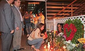 La madre de Mikel, acompañada de su marido, deposita una vela ante la foto de su hijo esta pasada medianoche en Portugalete. :: MITXEL ATRIO/