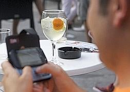 Un joven consulta su teléfono mientras degusta un gin-tonic./