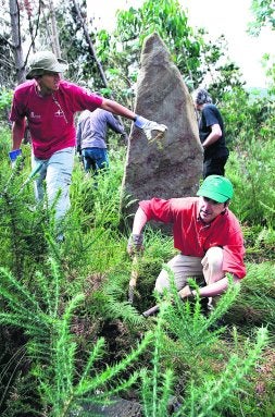 Voluntarios limpian el menhir de Busturia. / M. S./
