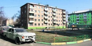 Un coche abandonado junto a uno de los parques de juego de una ciudad en continuo crecimiento./