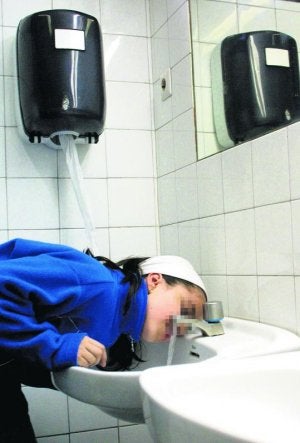 Una niña bebe agua en el baño de un colegio vitoriano. :: BLANCA CASTILLO/