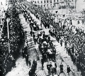 El cortejo fúnebre desfila por el puente de El Arenal, entonces de Isabel II, cuyas farolas estaban enlutadas con crespones. :: EL PUEBLO VASCO/