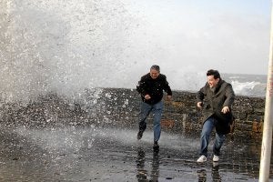 Una ola sorprende a dos personas que se hacían una foto en San Sebastián. /G. Rivas/