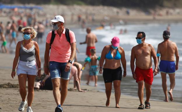 Varios turistas pasean con mascarilla por la playa del Inglés, en Gran Canaria. /reuters