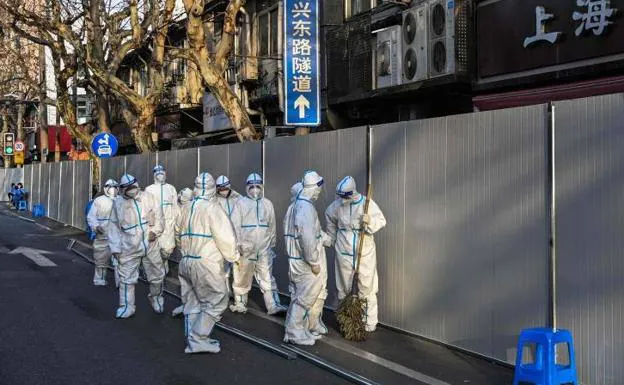 A group of workers dressed in protective suits walk past a barrier placed to confine a residential area in Shanghai following the detection of a covid outbreak, in March this year.